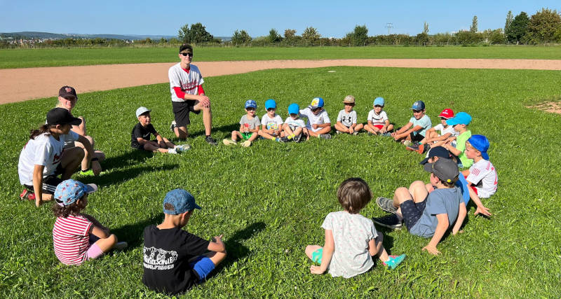 Kinder sitzen im Kreis auf dem Field
